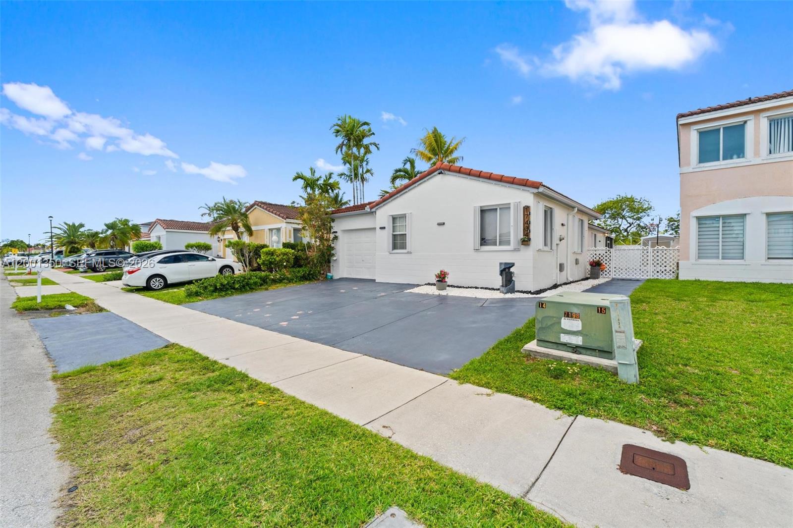 A white single-story house with a tiled roof and a paved driveway sits on a lawn — 17434 SW 143rd Pl, Miami FL 33177, MIAMI, FL