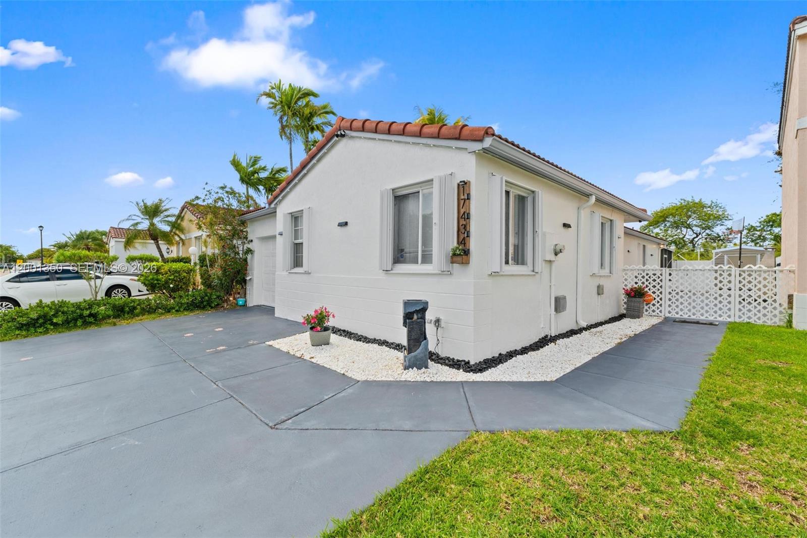 A white single-story house with a tiled roof and a paved driveway under a blue sky — 17434 SW 143rd Pl, Miami FL 33177, MIAMI, FL