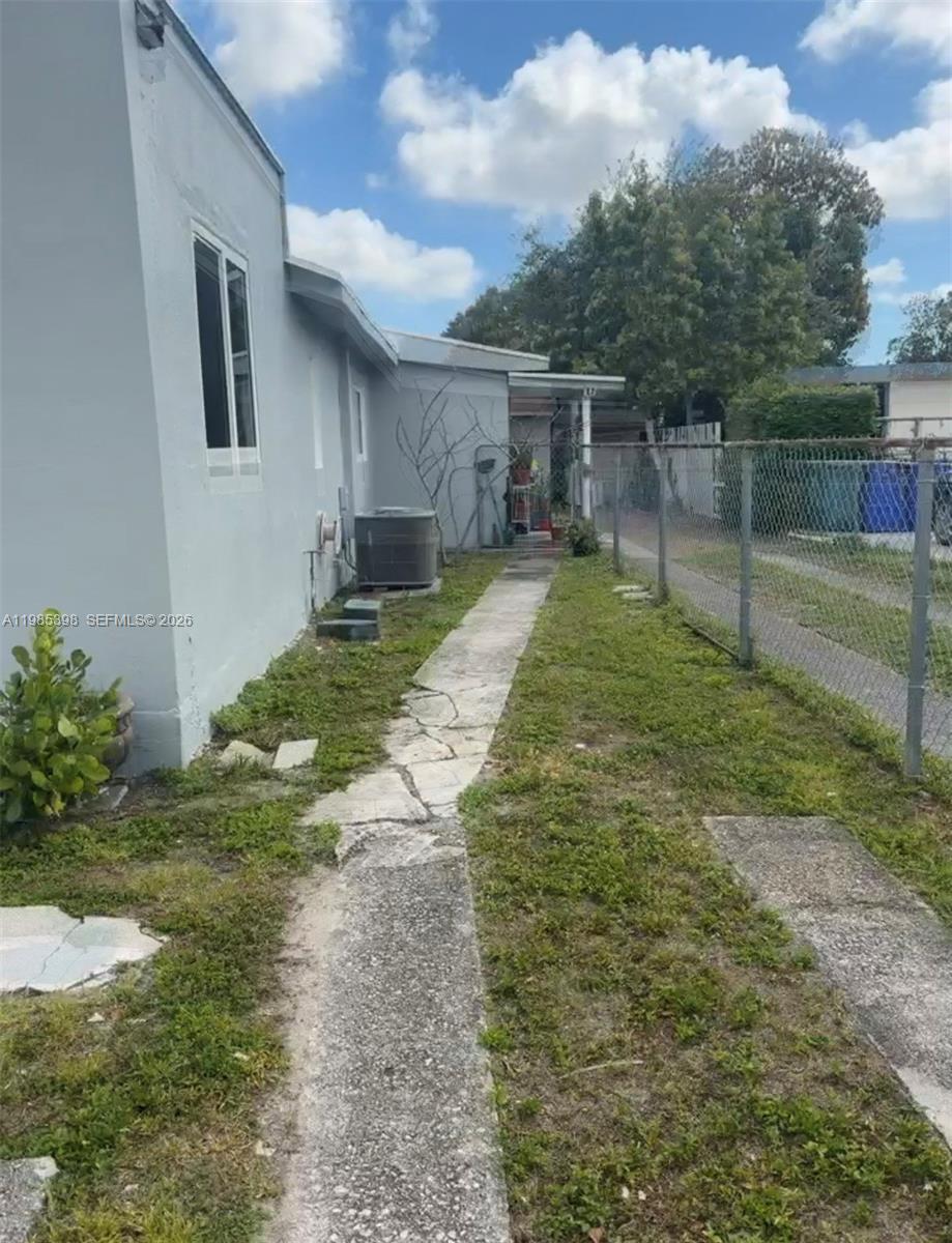 A narrow concrete walkway runs along the side of a gray house beside a fence — 1637 NW 31st Ave, Miami FL 33125, MIAMI, FL