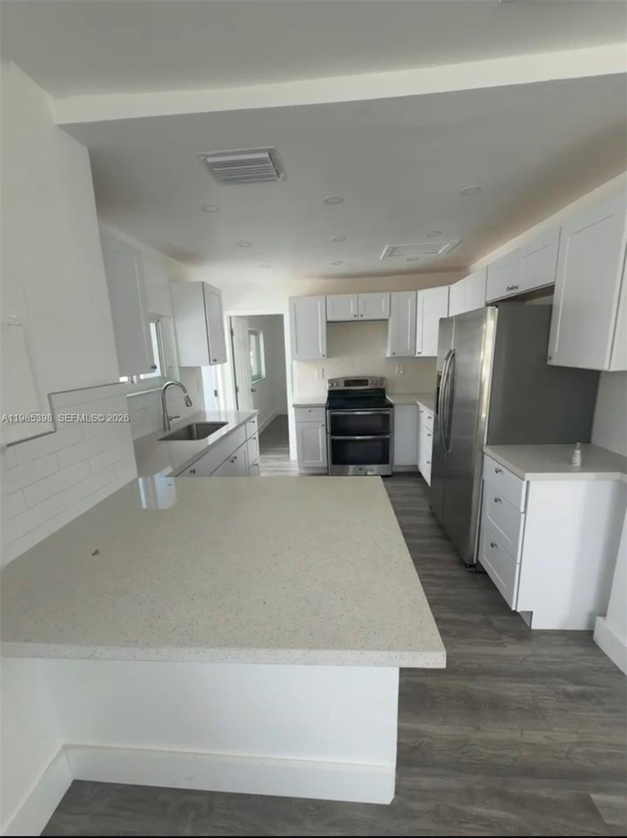 A kitchen features white cabinetry, quartz countertops, stainless steel appliances, and gray wood-look flooring — 1637 NW 31st Ave, Miami FL 33125, MIAMI, FL