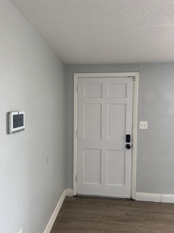 A white six-panel door is centered on a light gray wall with wood-look flooring — 1435 WHITEHALL LANE, HOLIDAY, FL