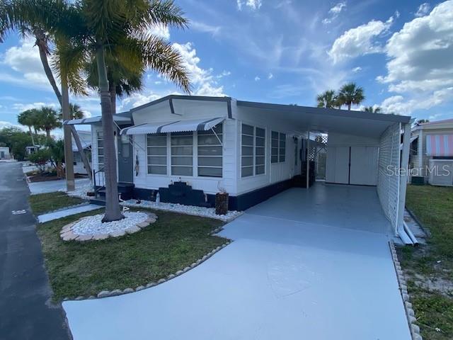 A white mobile home with a carport and a palm tree in the front yard — 4851 W GANDY BOULEVARD UNIT B10L30, TAMPA, FL