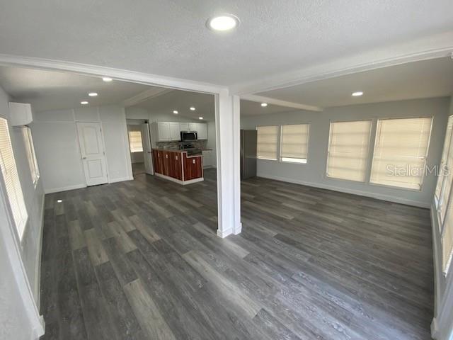 A living room with gray wood-look flooring opens into a kitchen with white cabinets — 4851 W GANDY BOULEVARD UNIT B10L30, TAMPA, FL