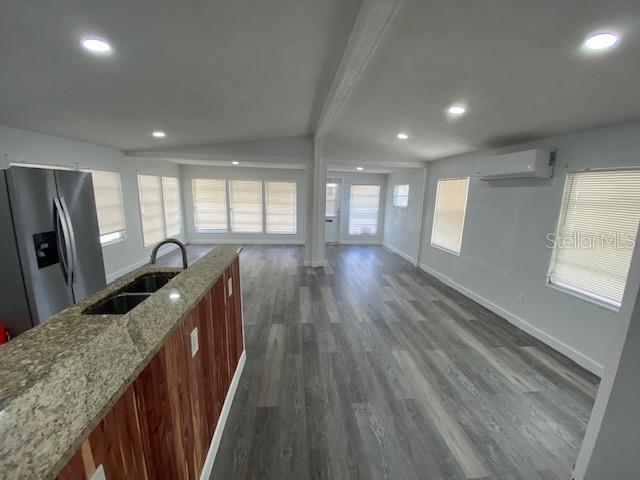 A kitchen with granite countertops and a stainless steel refrigerator overlooks a spacious living area — 4851 W GANDY BOULEVARD UNIT B10L30, TAMPA, FL