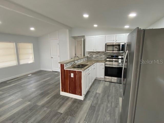 A kitchen with white cabinets, stainless steel appliances, and a wood-paneled island peninsula — 4851 W GANDY BOULEVARD UNIT B10L30, TAMPA, FL