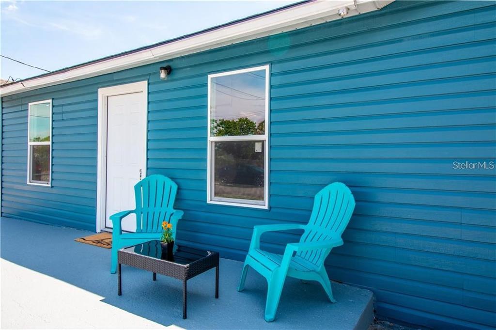 A blue house exterior features a white door, two windows, and two turquoise chairs — 7508 CAROLYN AVENUE, ORLANDO, FL