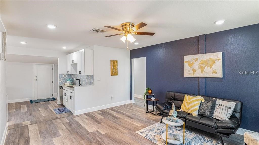 A living room features a kitchenette, a black sofa, and a dark blue accent wall — 7508 CAROLYN AVENUE, ORLANDO, FL