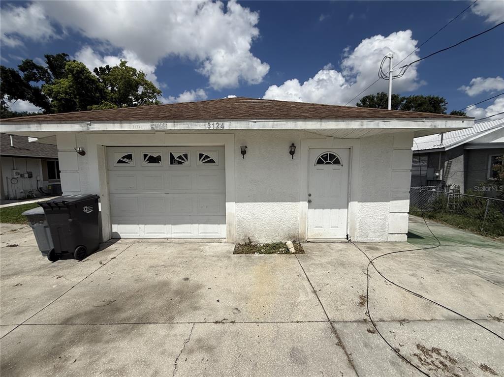 A detached white stucco garage with a single-car door and a side entry door — 3124 11TH STREET COURT E, BRADENTON, FL