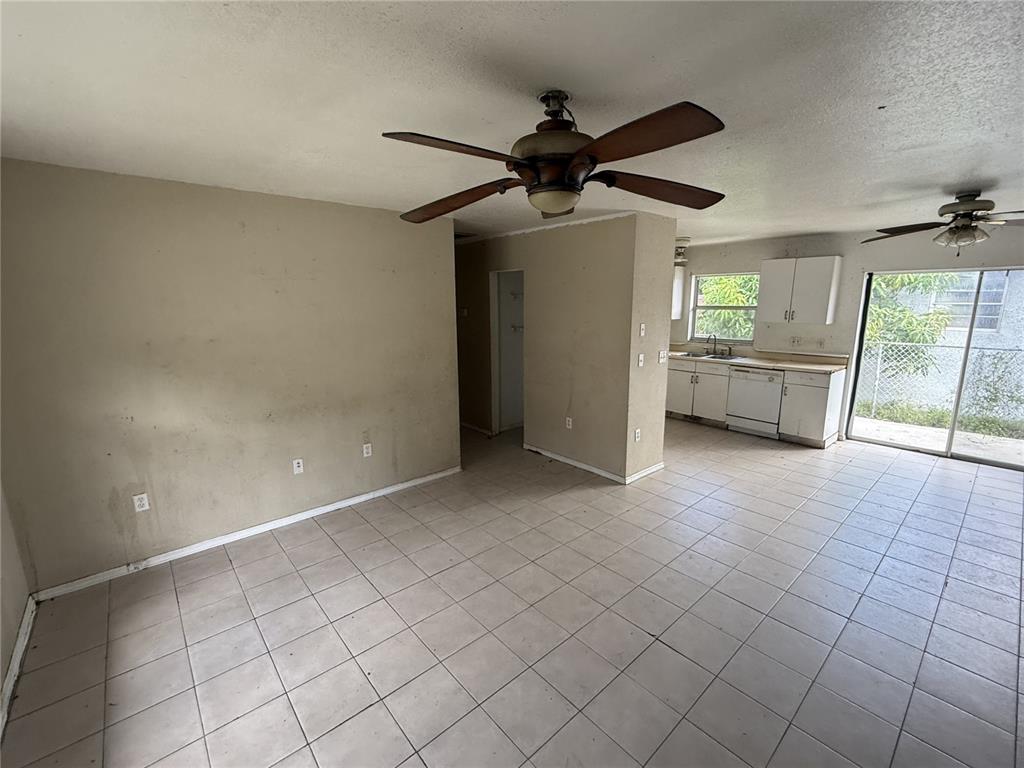 An open-concept living and kitchen area features beige walls, tile flooring, and two ceiling fans — 3124 11TH STREET COURT E, BRADENTON, FL