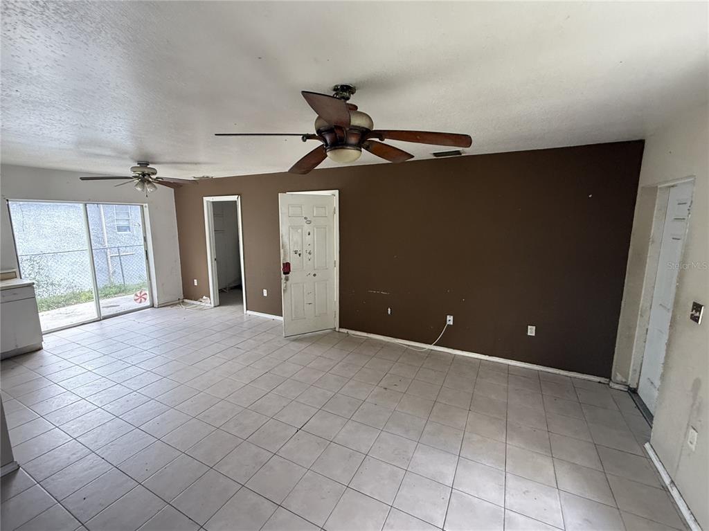 A room with light-colored tile flooring, a brown accent wall, and two ceiling fans — 3124 11TH STREET COURT E, BRADENTON, FL