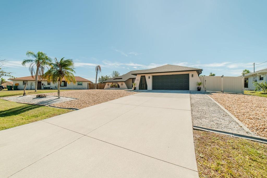 A single-story house with a large concrete driveway and a gravel front yard — 9273 CARNATION AVENUE, ENGLEWOOD, FL
