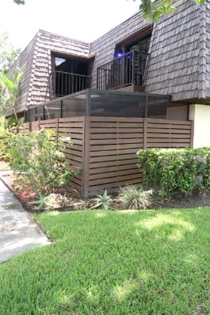 A brown wooden fence encloses a patio area in front of a multi-story building — 15202 E POND WOODS DRIVE UNIT 9, TAMPA, FL