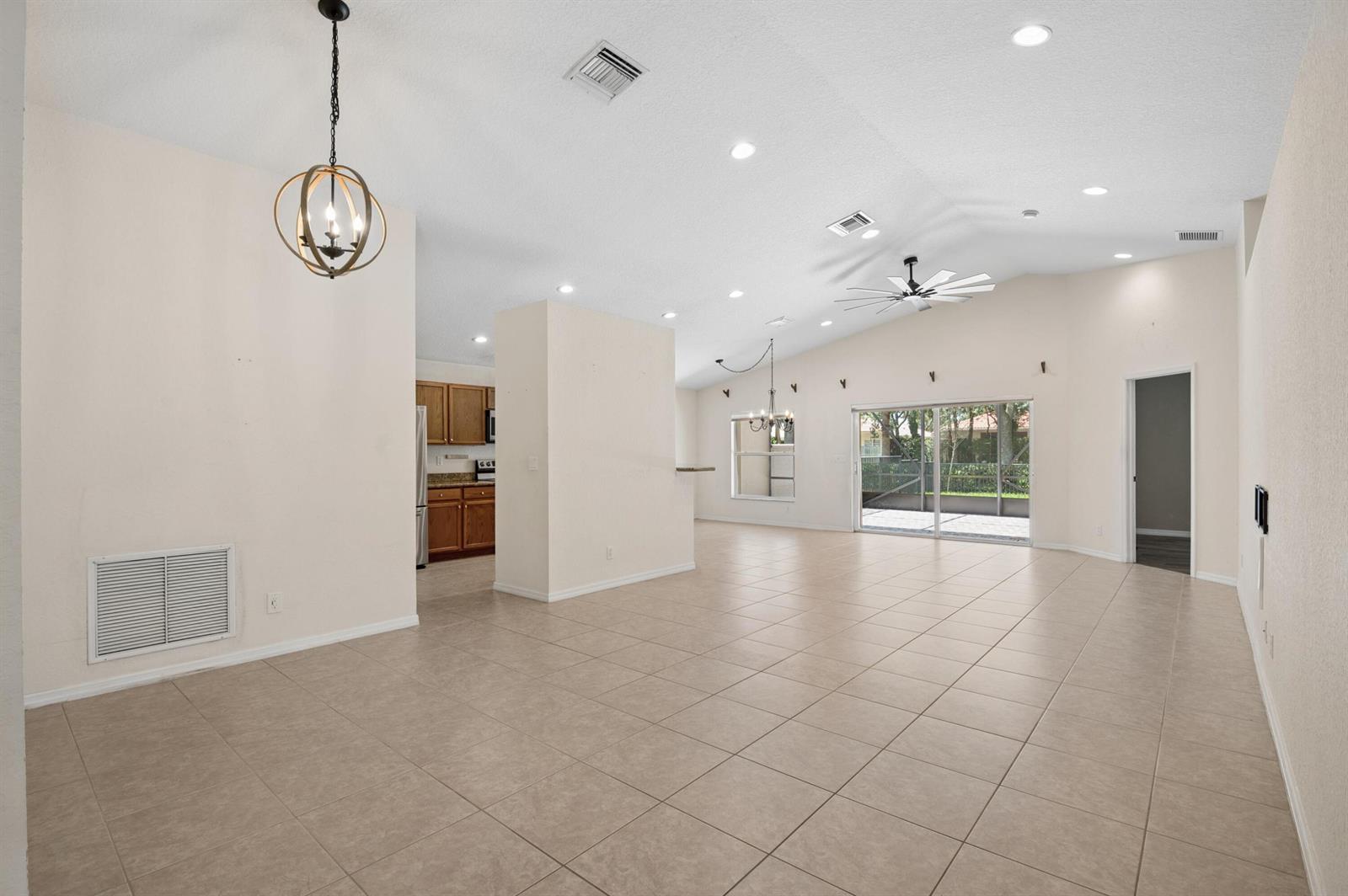An open-concept living area features vaulted ceilings, tile flooring, a kitchen, and sliding glass doors — 5330 Vernio Lane, Boynton Beach FL 33437, BOYNTON BEACH, FL