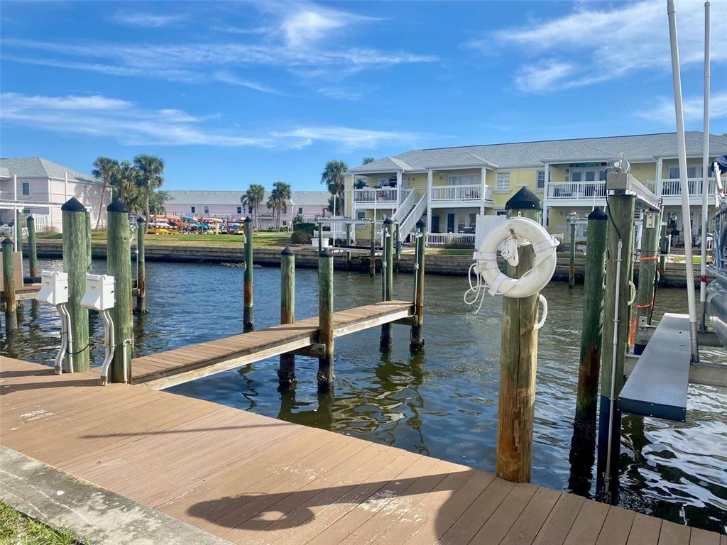 A wooden dock extends into a canal toward a multi-story building with balconies — 0 NE BEACH DRIVE SE UNIT 95SS, ST PETERSBURG, FL