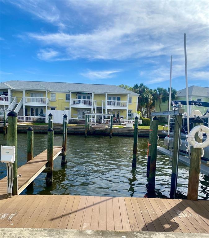 A wooden boat dock overlooks a canal with a multi-story yellow apartment building beyond — 0 NE BEACH DRIVE SE UNIT 95SS, ST PETERSBURG, FL
