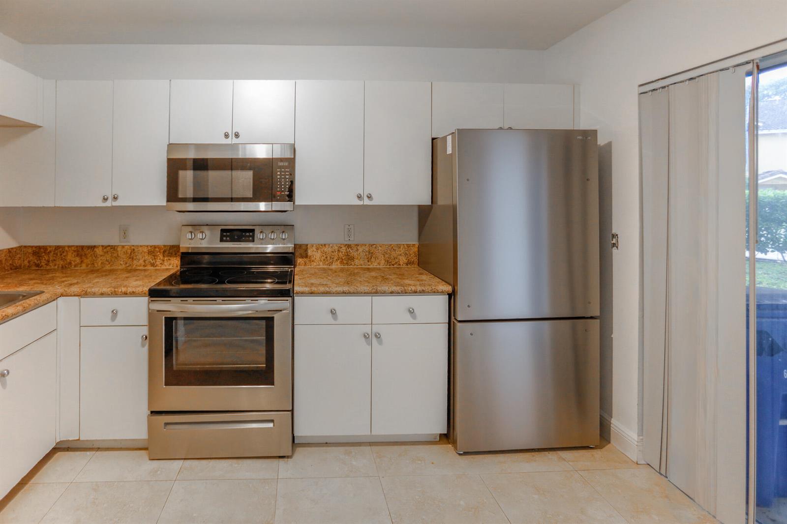 A kitchen features white cabinets, stainless steel appliances, and tan speckled countertops — 4149 NW 67th Te # 4149, Lauderhill FL 33319, LAUDERHILL, FL