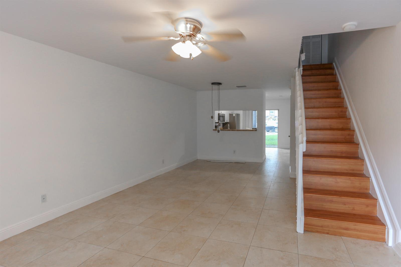 An open living area features tile flooring, a ceiling fan, and a wooden staircase — 4149 NW 67th Te # 4149, Lauderhill FL 33319, LAUDERHILL, FL