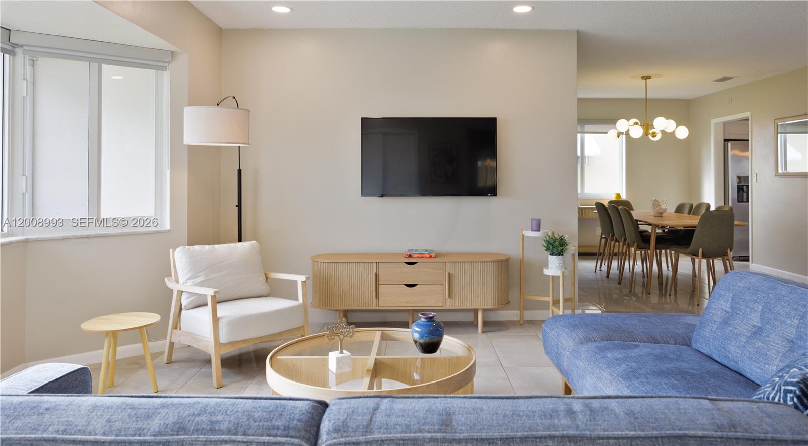 A living room features a blue sofa, a wooden media console, and a dining area — 609 S Crescent Dr, Hollywood FL 33021, HOLLYWOOD, FL