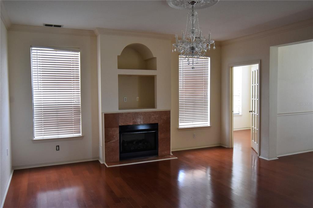 A living room features hardwood floors, a fireplace, a ceiling fan, and large windows — 2722 VIA TIVOLI UNIT 420A, CLEARWATER, FL