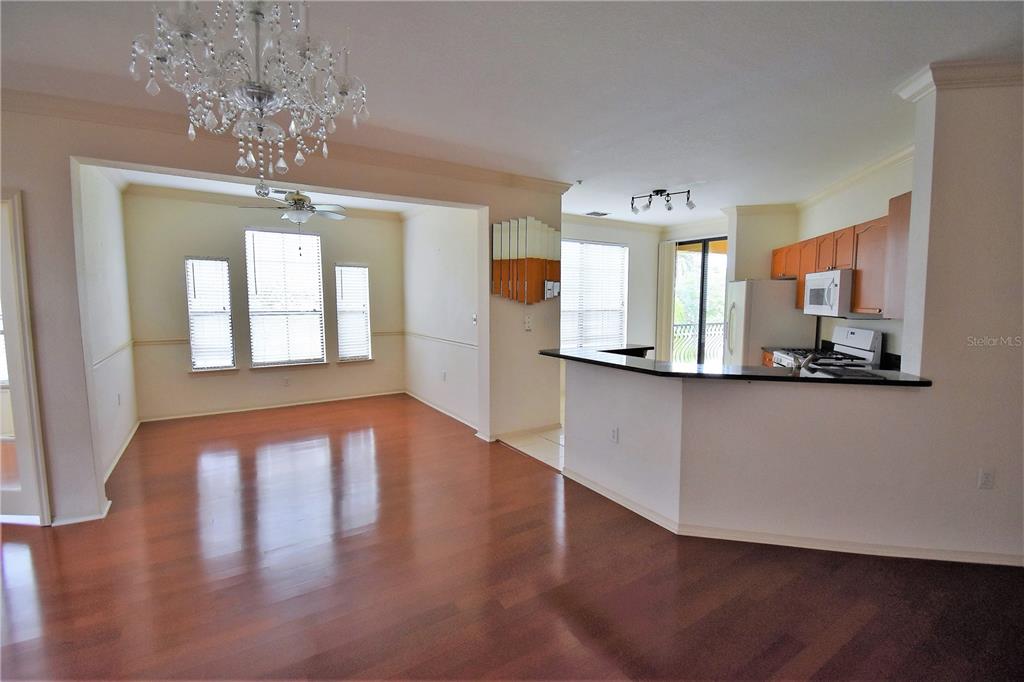 An open-concept living area features hardwood floors, a ceiling fan, and an adjacent kitchen — 2722 VIA TIVOLI UNIT 420A, CLEARWATER, FL
