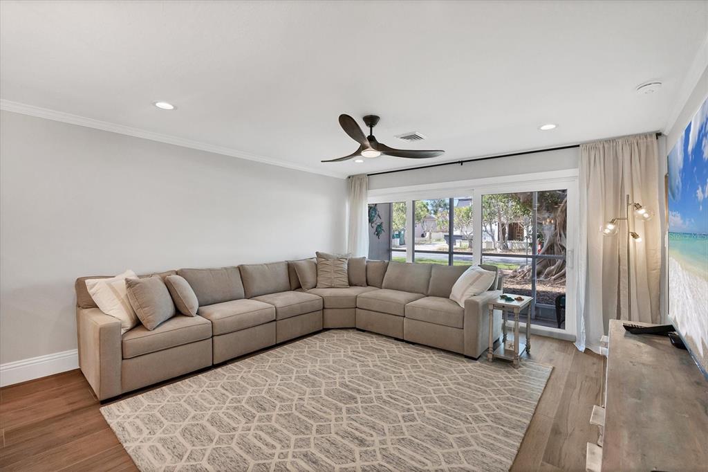 A living room features a large sectional sofa, a patterned rug, and sliding glass doors — 500 S WASHINGTON DRIVE UNIT 11A, SARASOTA, FL