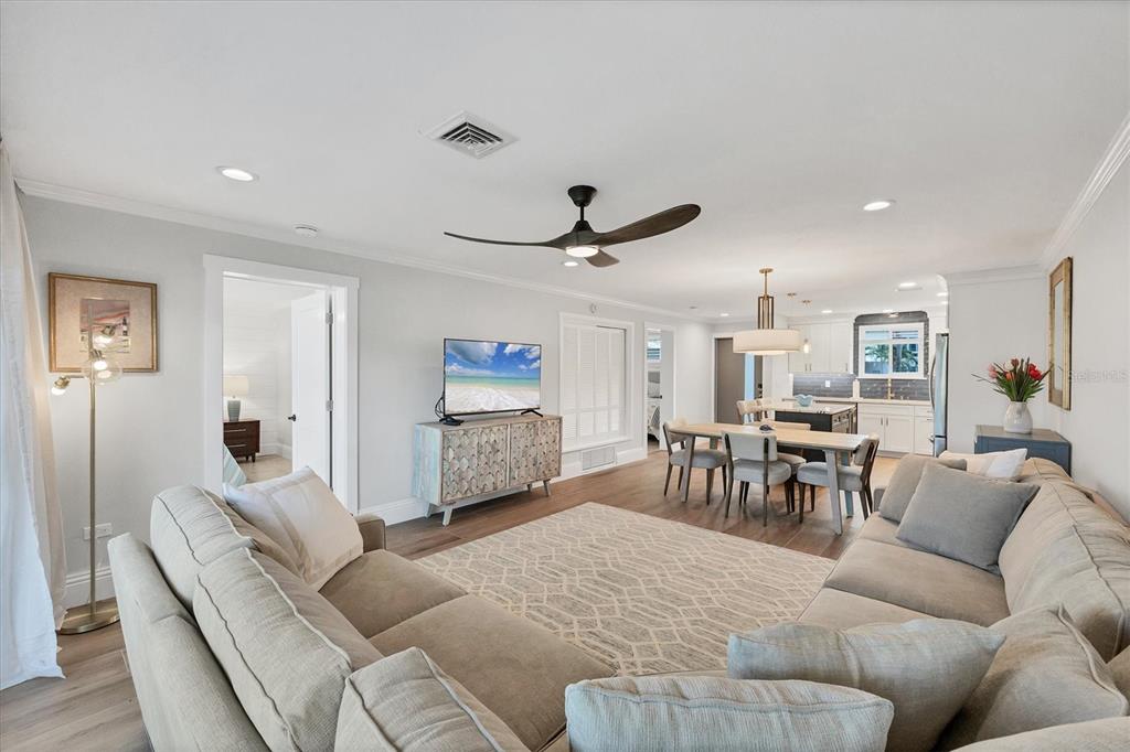 An open-concept living and dining area features light wood flooring, neutral furniture, and a kitchen — 500 S WASHINGTON DRIVE UNIT 11A, SARASOTA, FL