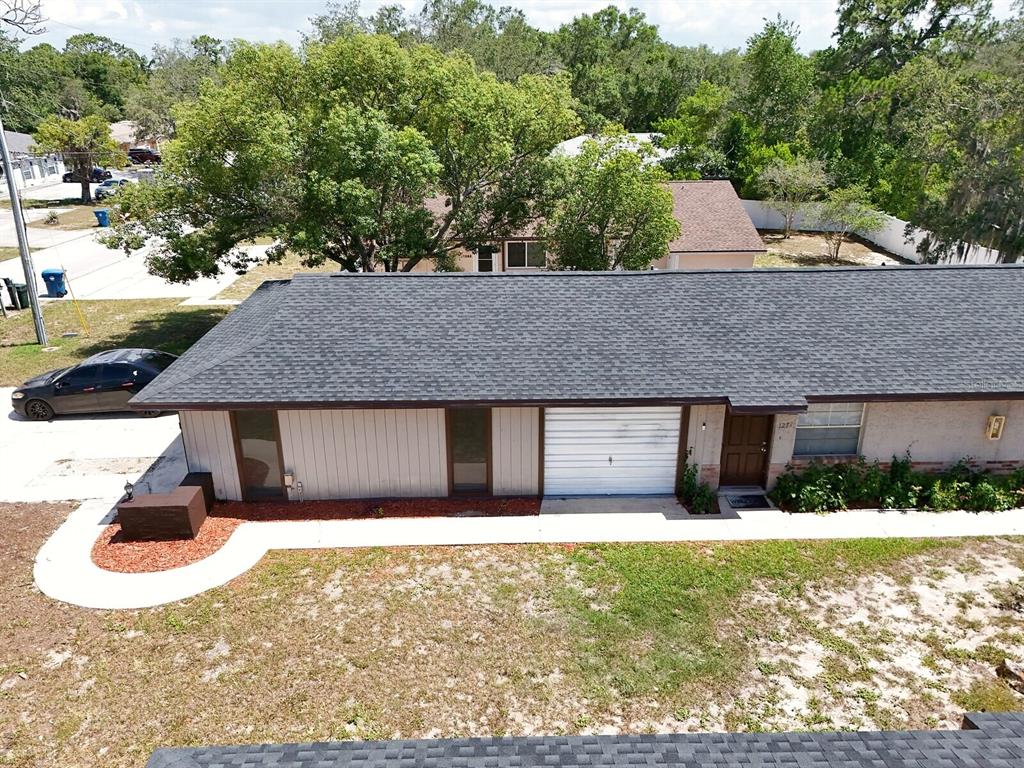 An aerial view shows the exterior of a single-story house with a dark shingled roof — 1277 SYLVIA AVENUE, SPRING HILL, FL