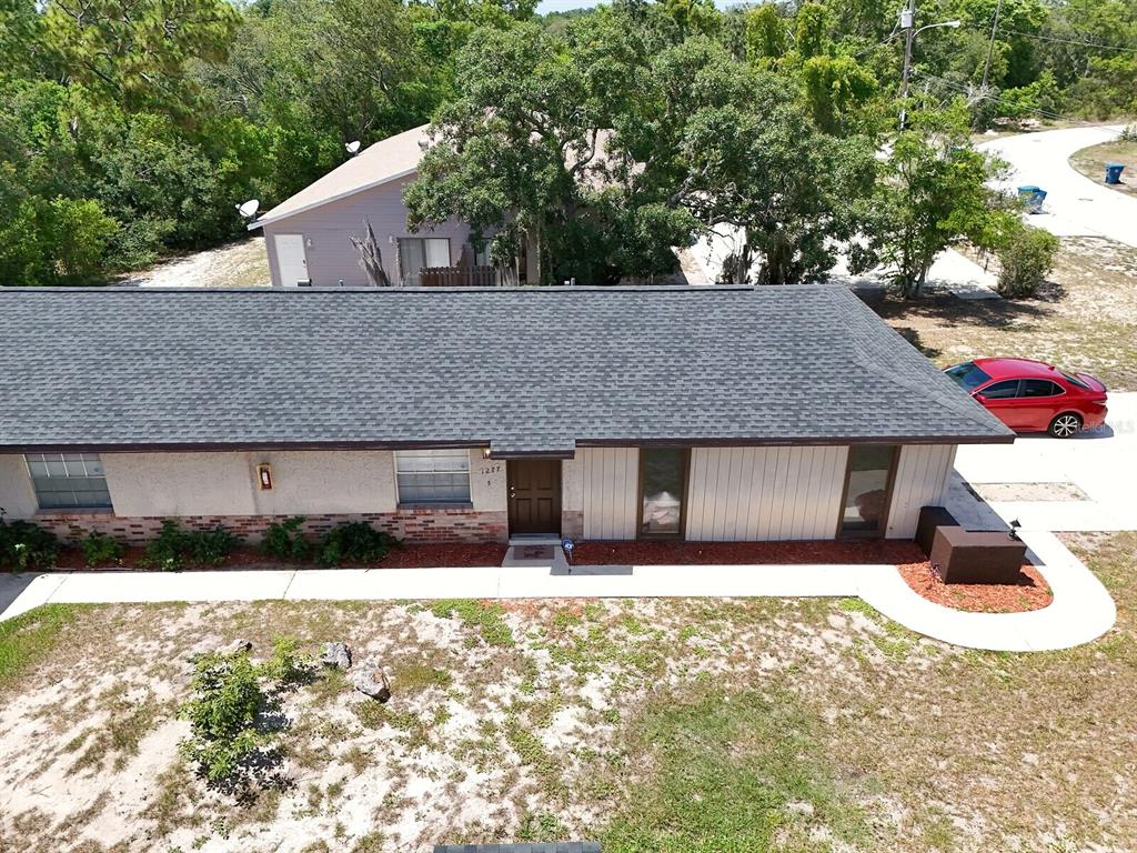 An aerial view of a single-story house with a dark shingled roof and brick accents — 1277 SYLVIA AVENUE, SPRING HILL, FL