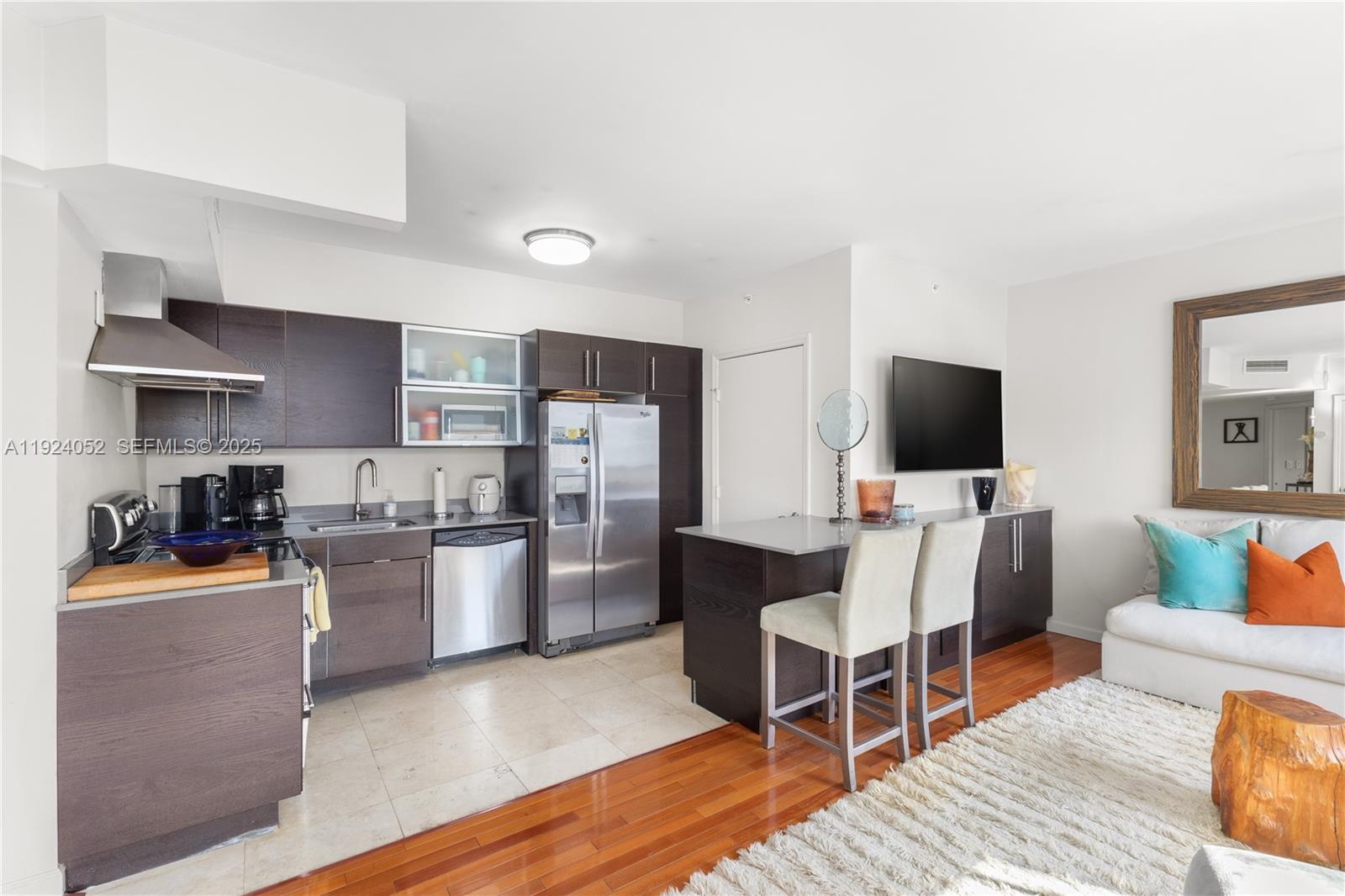 This kitchen and living area features dark wood cabinetry, stainless steel appliances, and hardwood flooring — 1330 West Ave # 1712, Miami Beach FL 33139, MIAMI BEACH, FL