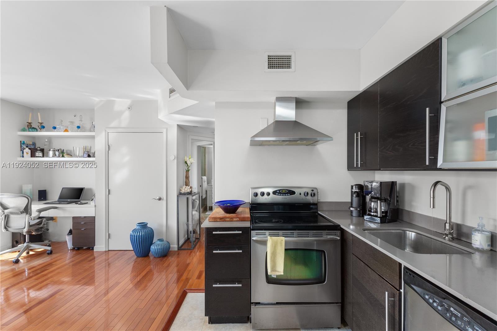 A kitchen with dark wood cabinets, stainless steel appliances, and an adjacent home office area — 1330 West Ave # 1712, Miami Beach FL 33139, MIAMI BEACH, FL