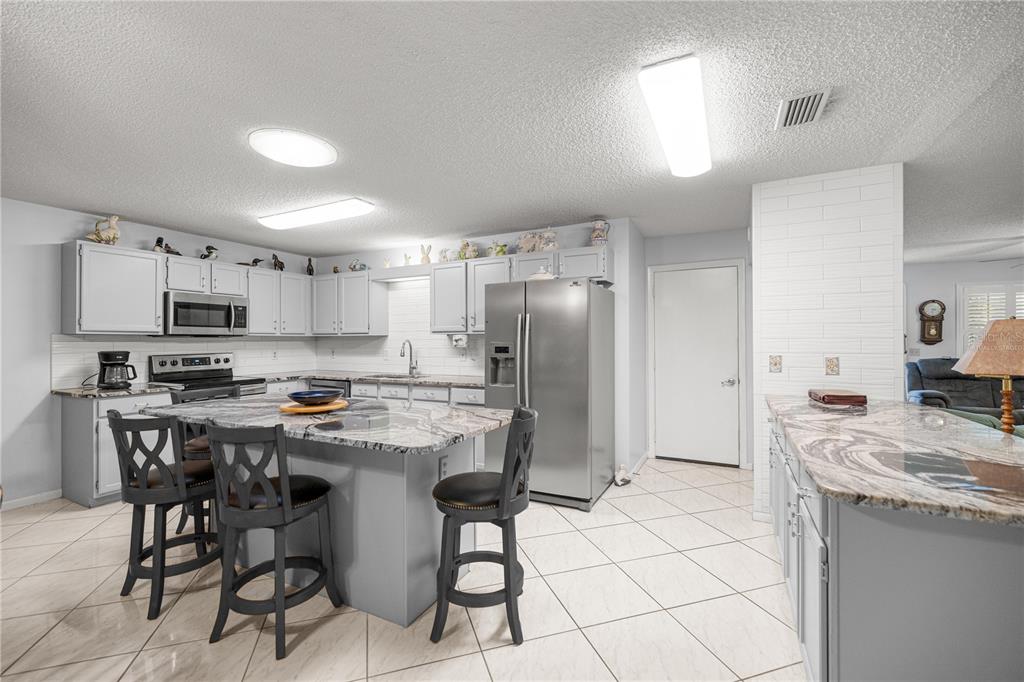 A living room with wood-look tile flooring transitions into a tiled dining area — 9438 SW 85TH AVENUE UNIT B, OCALA, FL
