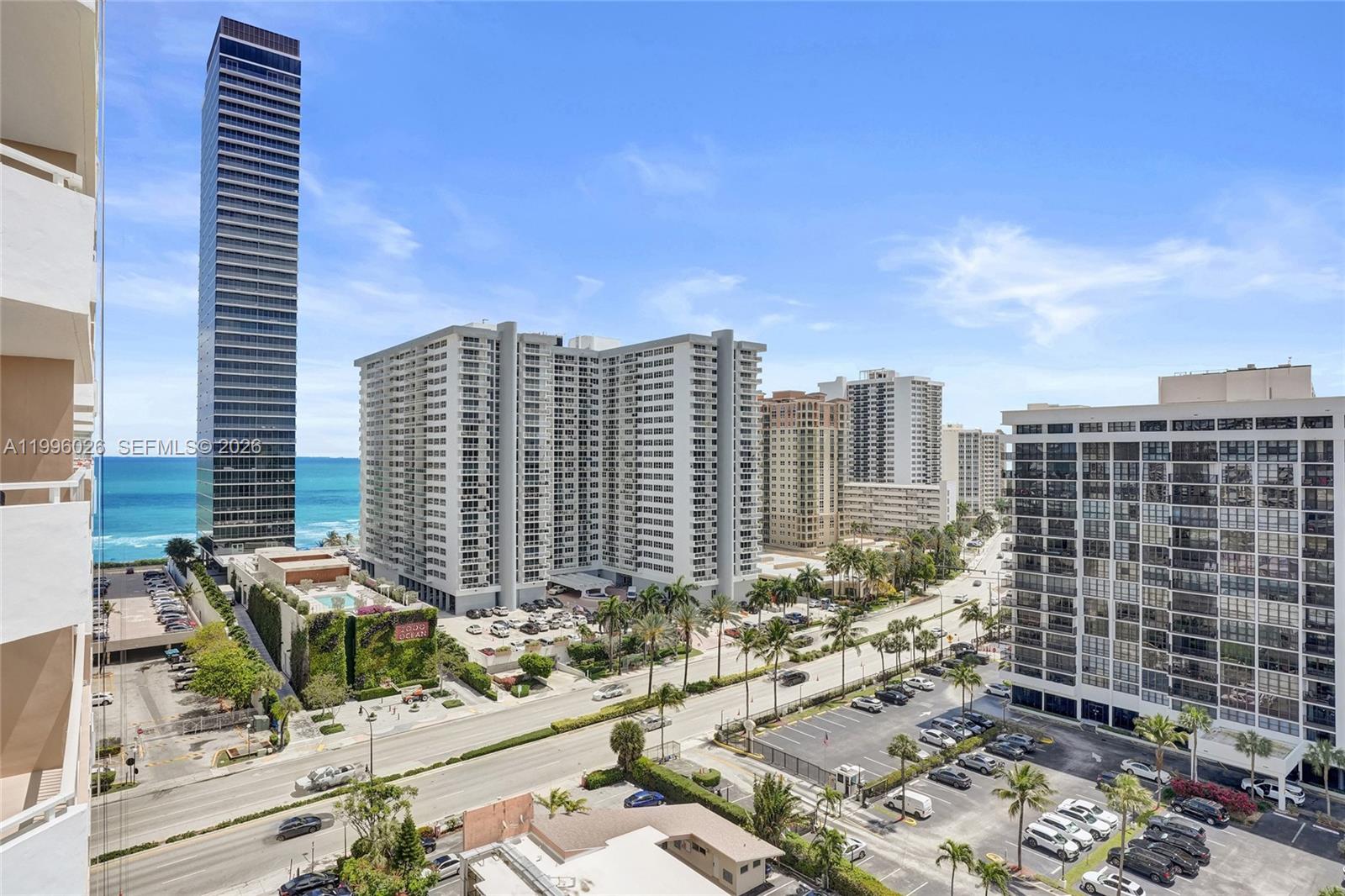 An elevated exterior view shows multiple high-rise apartment buildings and a parking lot near the ocean — 1985 S Ocean Dr # 12A, Hallandale Beach FL 33009, HALLANDALE BEACH, FL