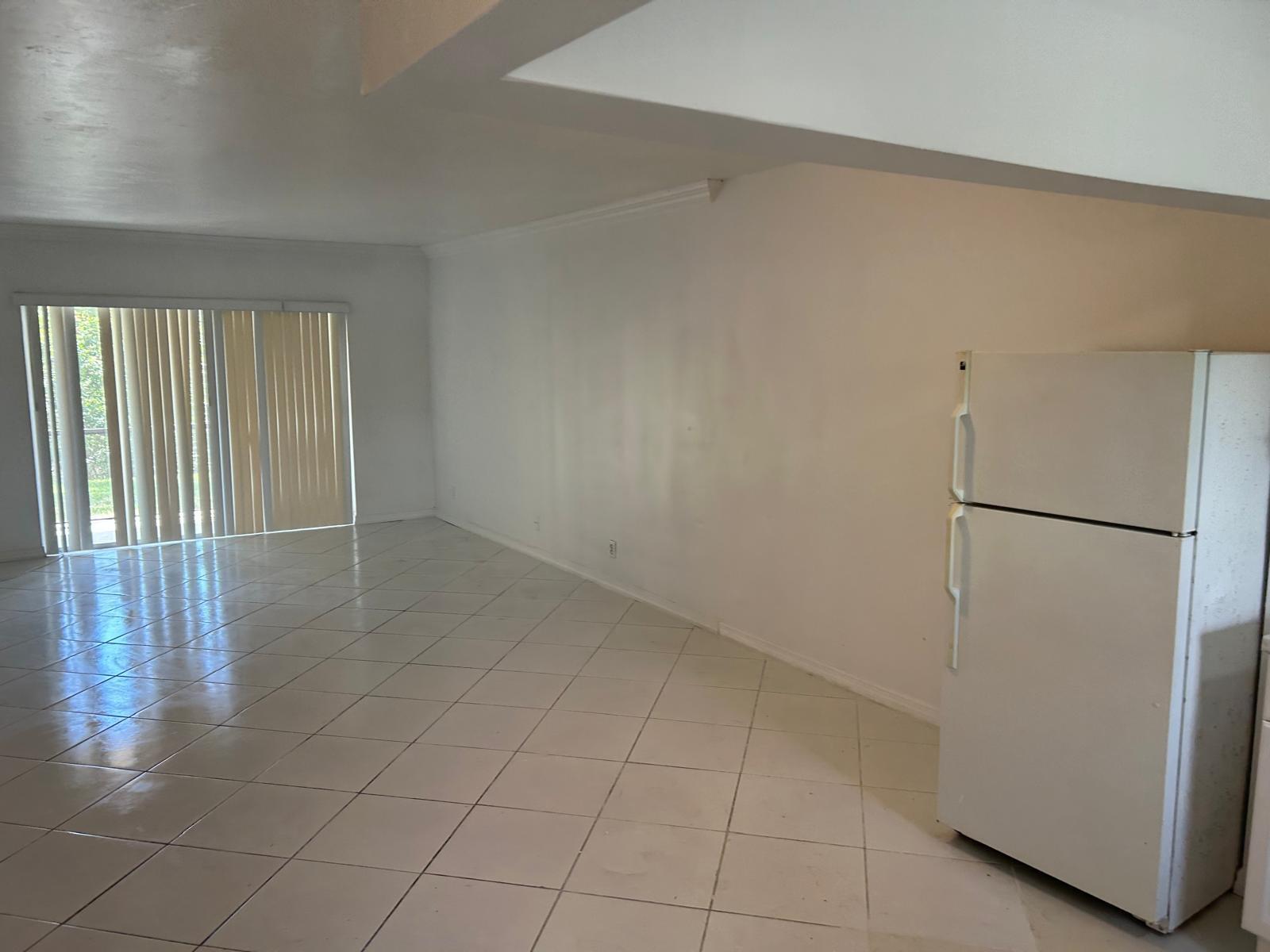 An open-concept room with white tile flooring, white walls, and a white refrigerator — 3900 NW 76th Avenue # 107, Sunrise FL 33351, SUNRISE, FL