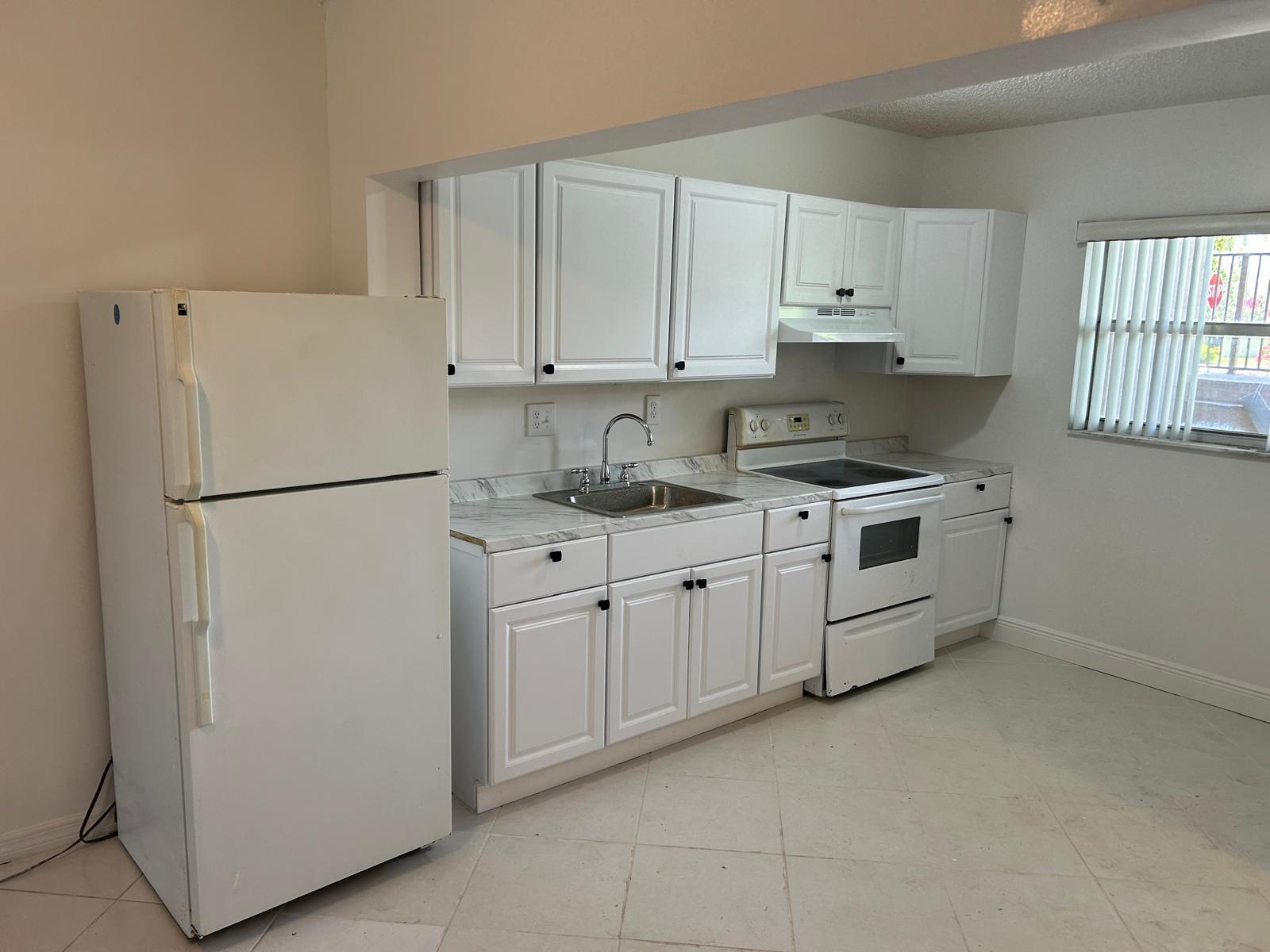 A kitchen with white cabinets, white appliances, and marble-look countertops on a tiled floor — 3900 NW 76th Avenue # 107, Sunrise FL 33351, SUNRISE, FL