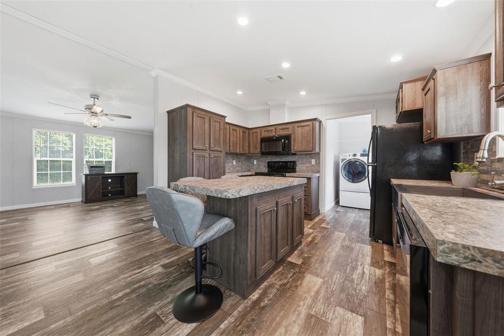A kitchen with dark wood cabinets, a center island, and a laundry room beyond — 6161 SE 145TH STREET, SUMMERFIELD, FL