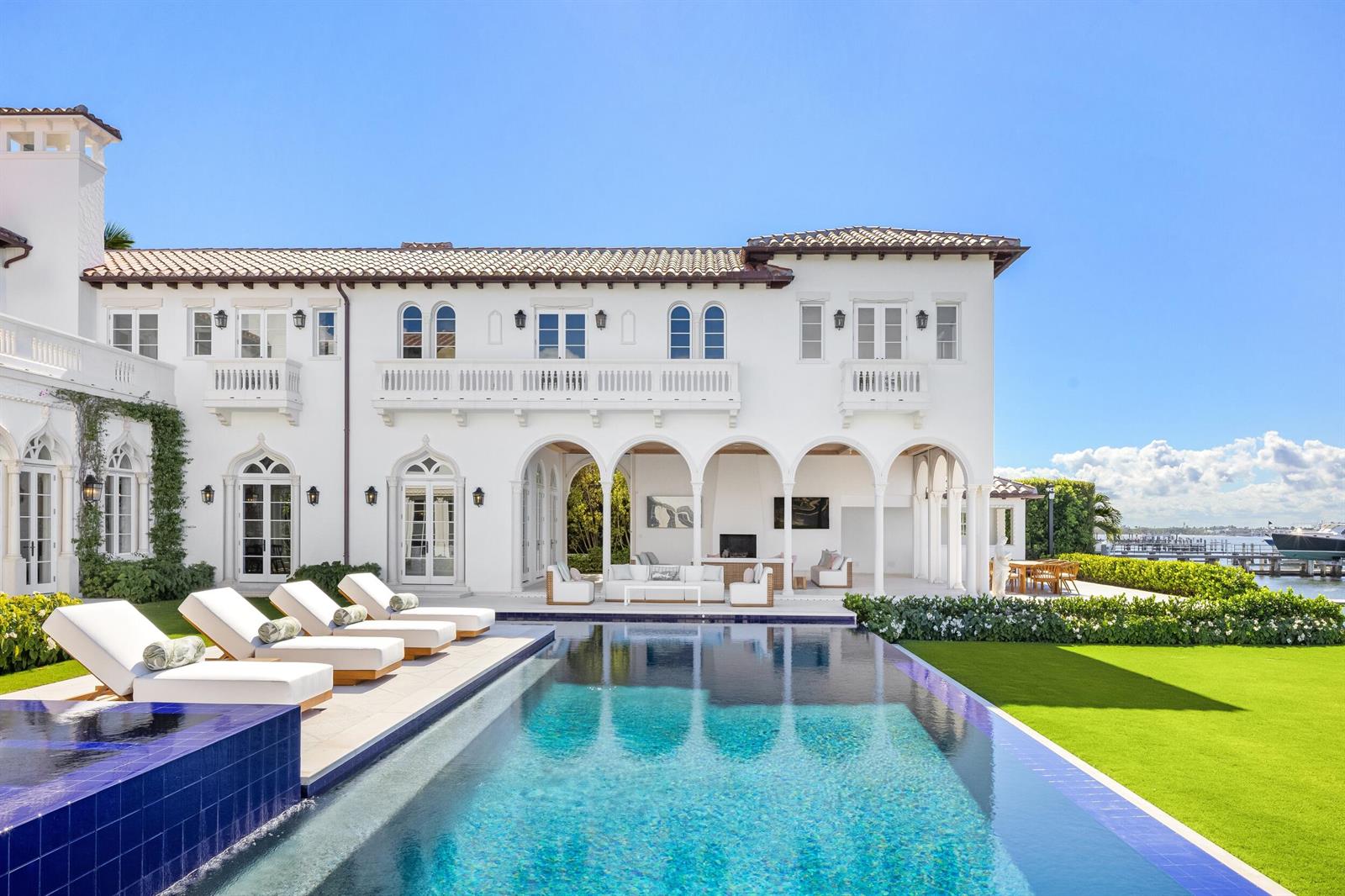 A white Mediterranean-style mansion features a swimming pool, lounge chairs, and a waterfront view — 800 S County Road, Palm Beach FL 33480, PALM BEACH, FL