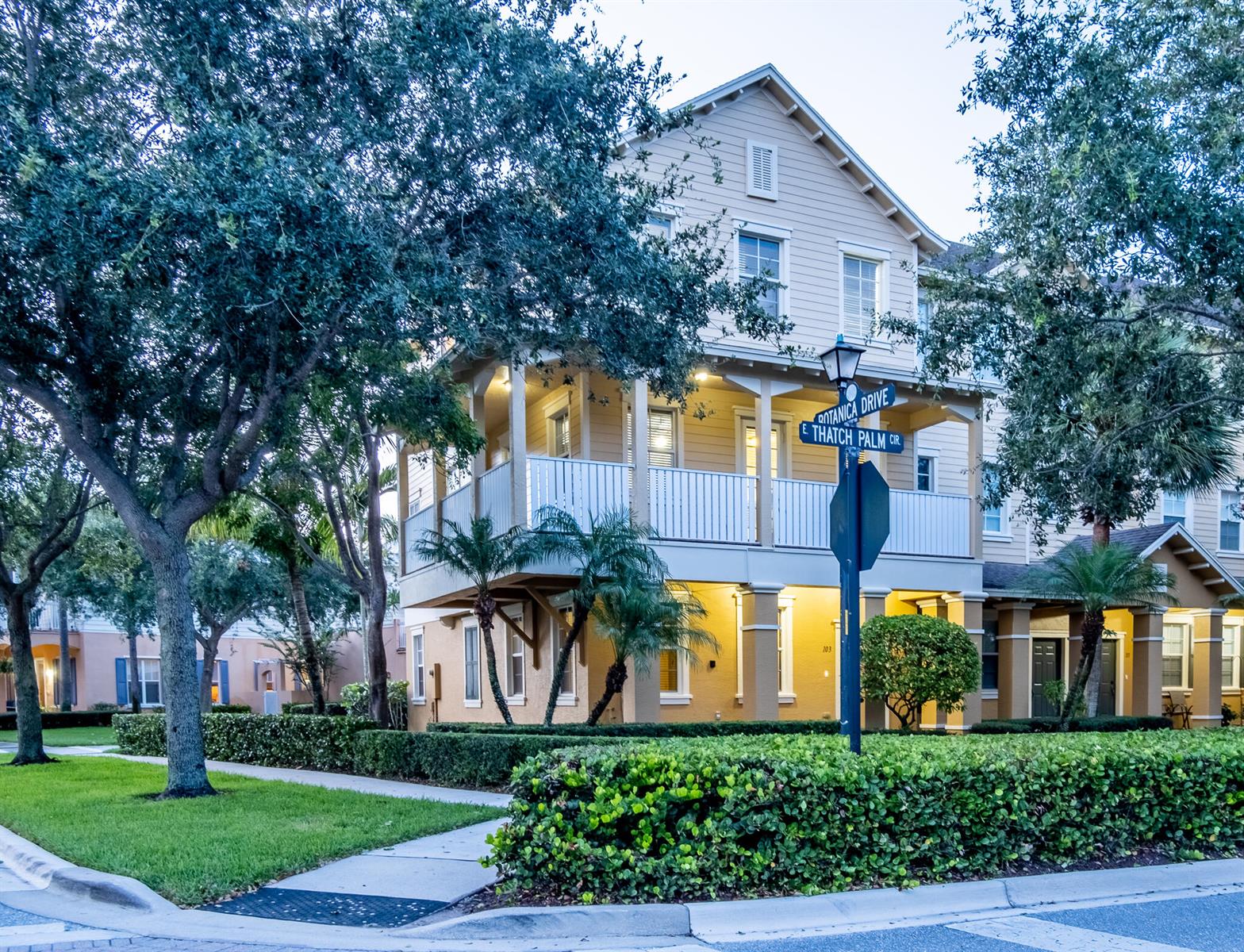 A three-story yellow house with a second-floor balcony stands at a street corner — 103 E Thatch Palm Circle, Jupiter FL 33458, JUPITER, FL