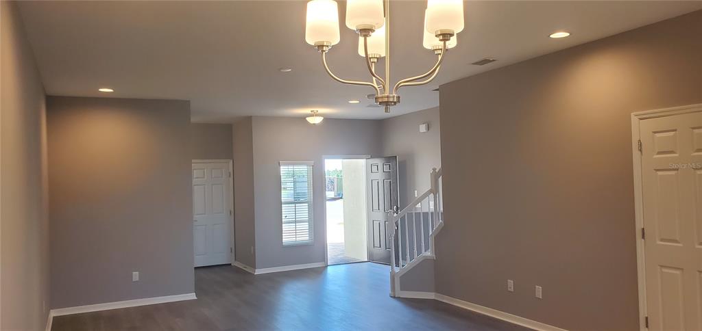 An interior view of a living area featuring gray walls, wood-look flooring, and a chandelier — 29821 SOUTHWELL LANE, WESLEY CHAPEL, FL