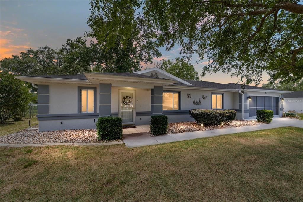 A single-story house with a gray and white exterior features a covered entryway and landscaping — 10169 SW 63RD AVENUE, OCALA, FL