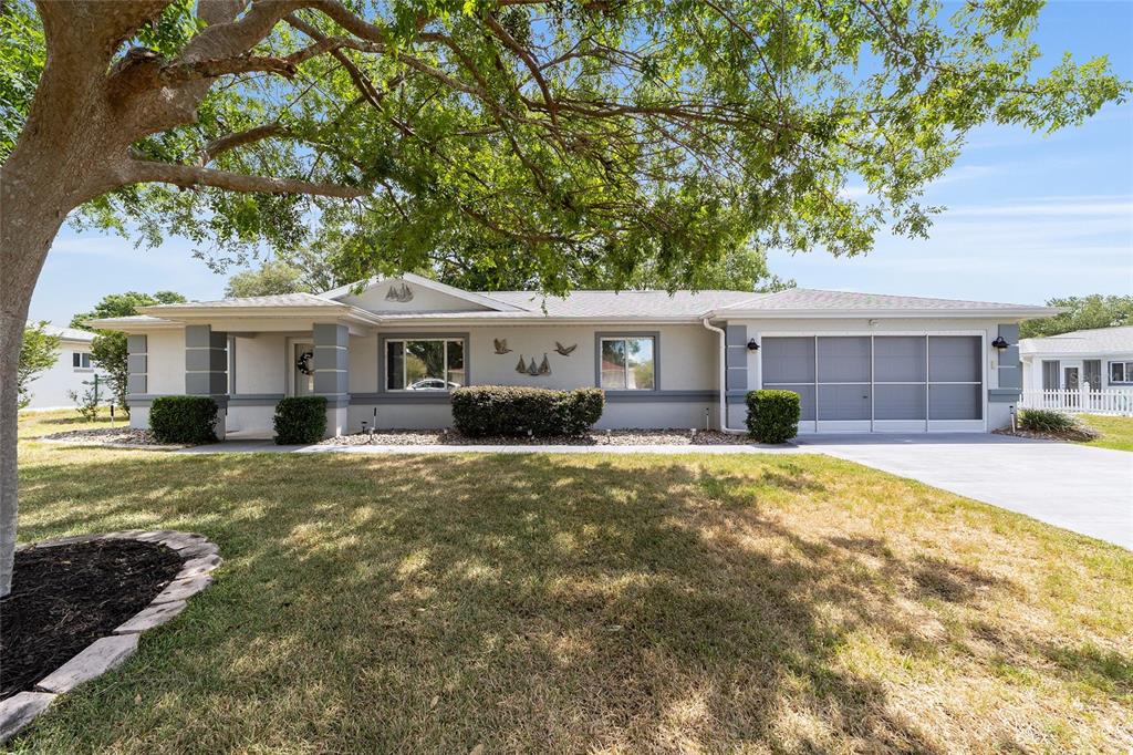 A single-story house with a gray exterior, a two-car garage, and a large shade tree — 10169 SW 63RD AVENUE, OCALA, FL
