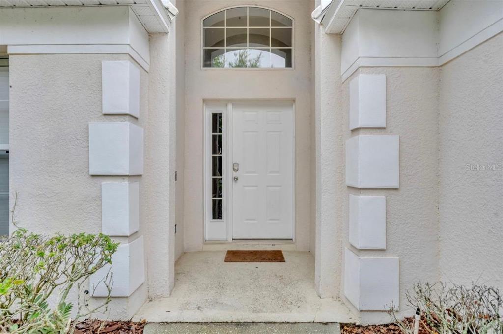A white front door with a side window and arched transom sits in a recessed entryway — 134 MADIERA BEACH BOULEVARD, KISSIMMEE, FL