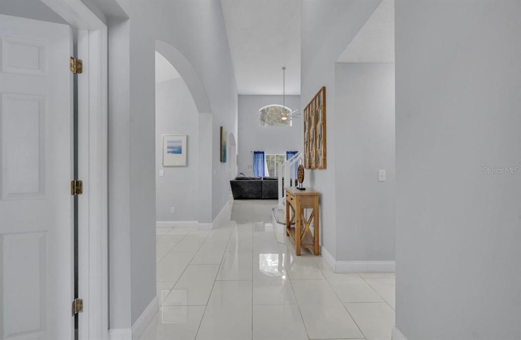 A bright hallway with white tile flooring leads toward an open living area — 134 MADIERA BEACH BOULEVARD, KISSIMMEE, FL