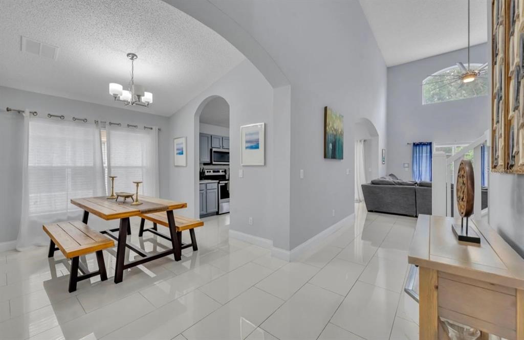A dining area with a wooden table and benches sits adjacent to a living room — 134 MADIERA BEACH BOULEVARD, KISSIMMEE, FL