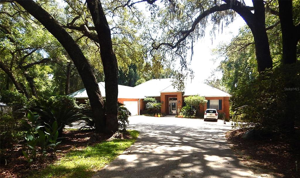 A single-story brick house with a white roof sits at the end of a driveway — 8315 LILLY LAKE ROAD, MELROSE, FL