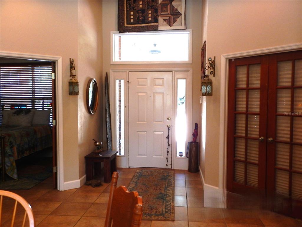 An entryway features a white front door with sidelights, tile flooring, and a high ceiling — 8315 LILLY LAKE ROAD, MELROSE, FL