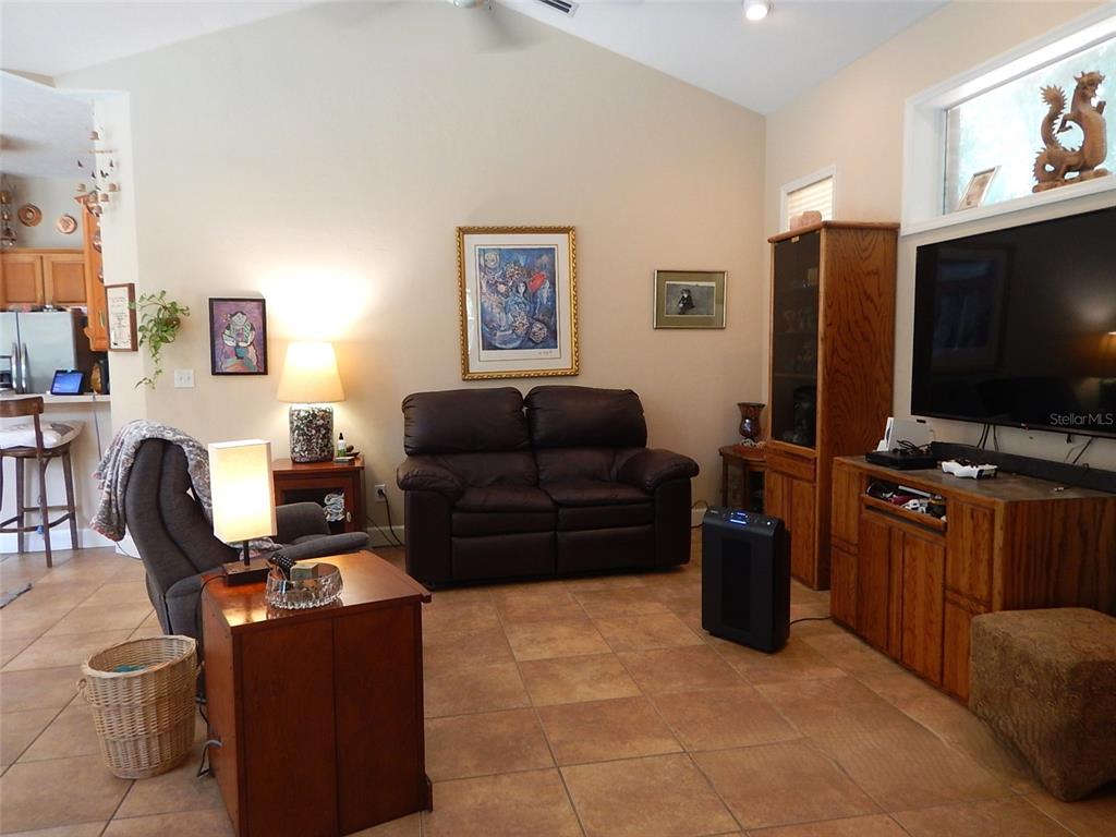 A living room features a brown loveseat, a recliner, tile flooring, and a television console — 8315 LILLY LAKE ROAD, MELROSE, FL
