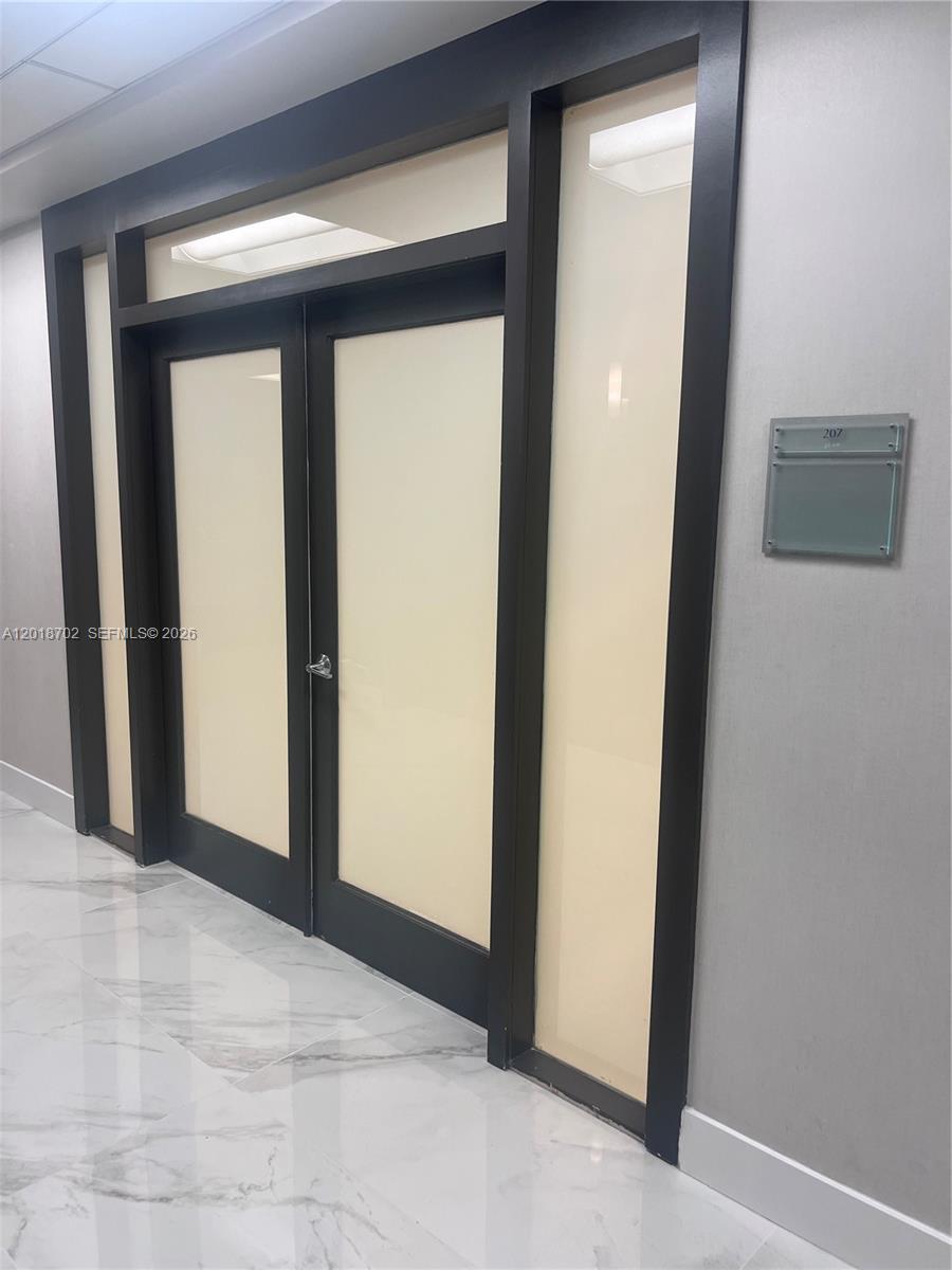 A double door with frosted glass panels and dark trim sits in a marble-floored hallway — 150 SE 2nd Ave # 208, Miami FL 33131, MIAMI, FL