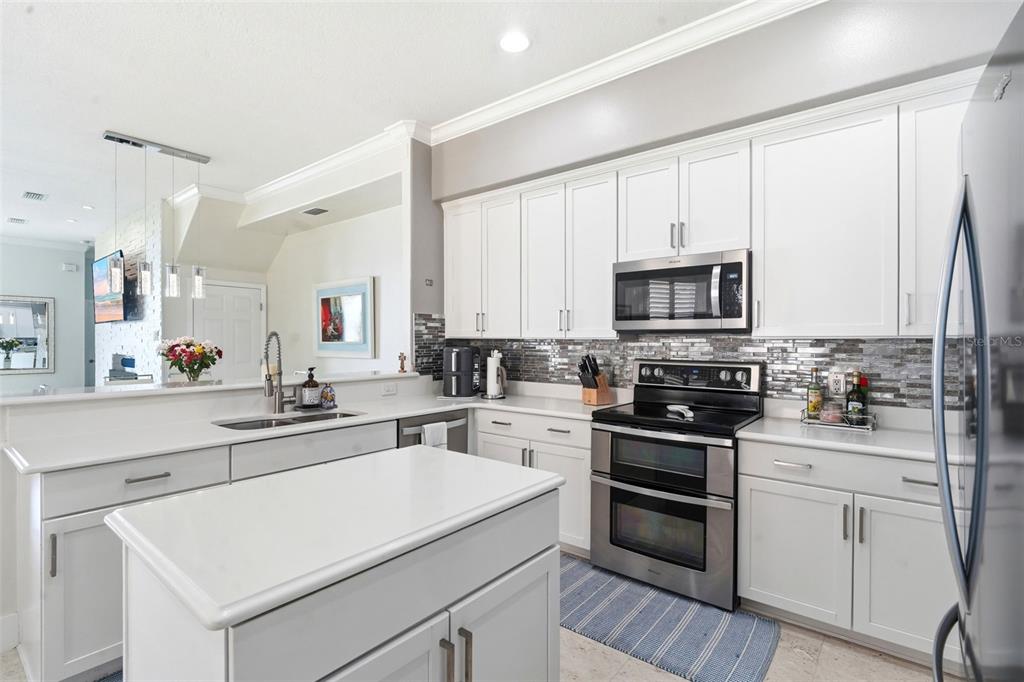 A modern kitchen features white cabinets, stainless steel appliances, and a central island — 8737 THE ESPLANADE UNIT 64, ORLANDO, FL