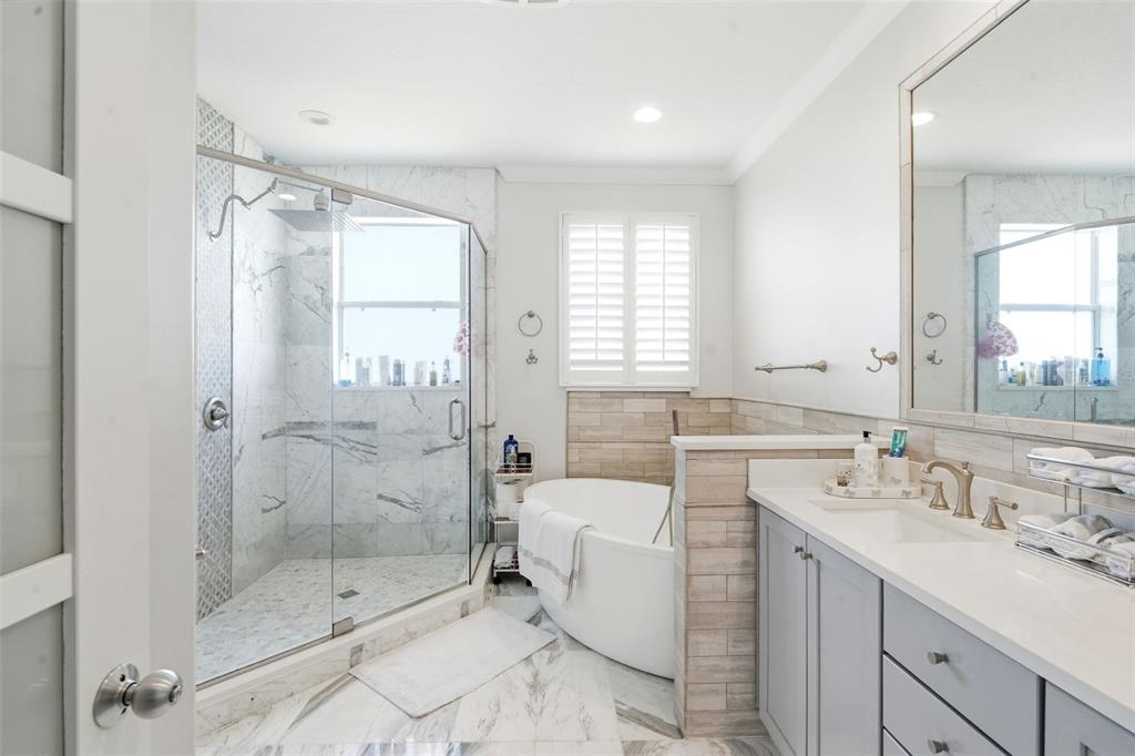 A bathroom features a glass-enclosed marble shower, a freestanding tub, and a gray vanity — 8737 THE ESPLANADE UNIT 64, ORLANDO, FL