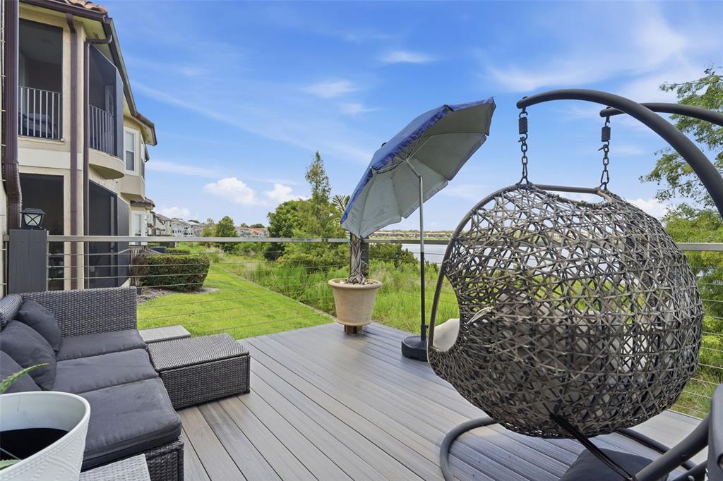 A deck with patio furniture, a hanging chair, and an umbrella overlooks a grassy area — 8737 THE ESPLANADE UNIT 64, ORLANDO, FL